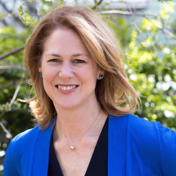 white woman with blonde hair wearing a blue sweater over a black shirt outside