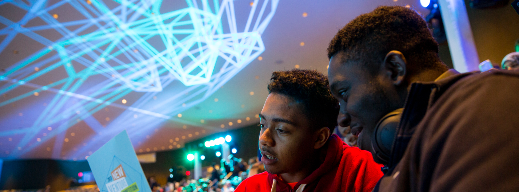 Students examining folder while lightshow plays on ceiling